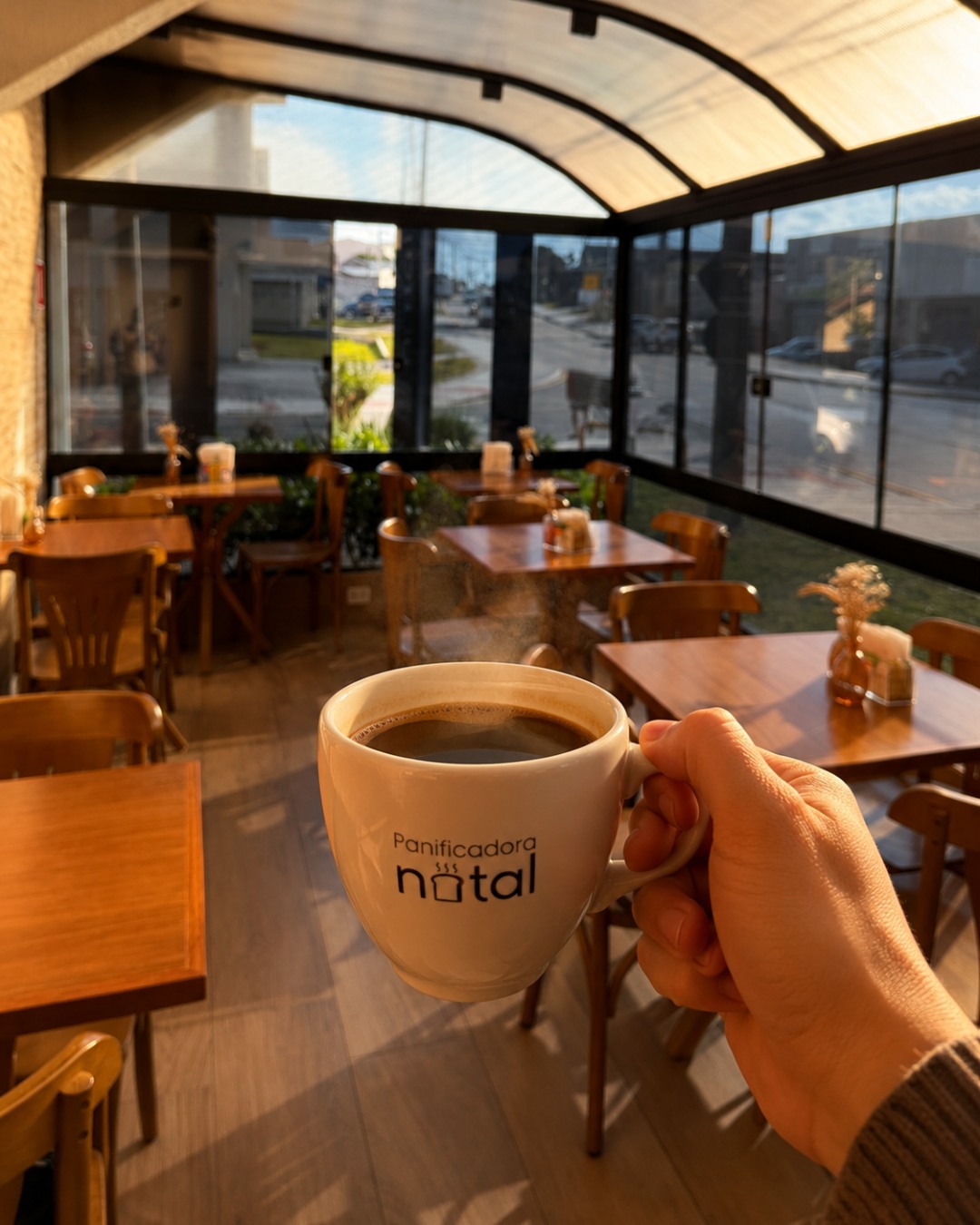 Uma xícara de café da Panificadora Natal, com o salão ao fundo